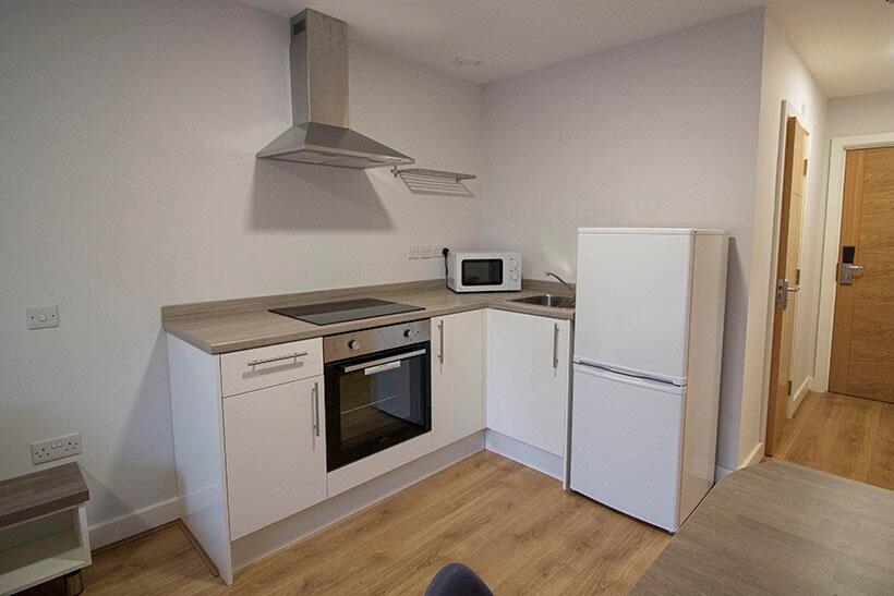 A modern, clean kitchen featuring white cabinet...