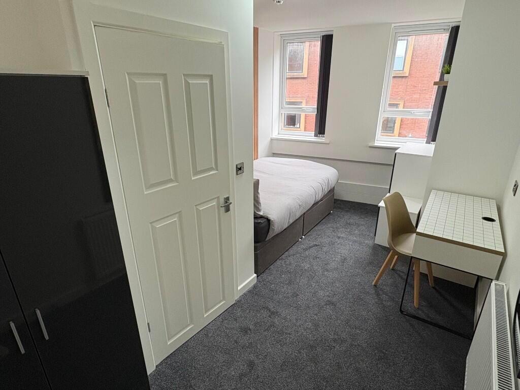 A neat and cozy single bedroom featuring a comf...