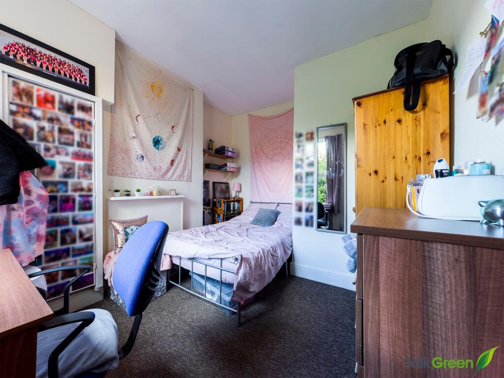 A cozy single bedroom featuring a bed, a desk w...