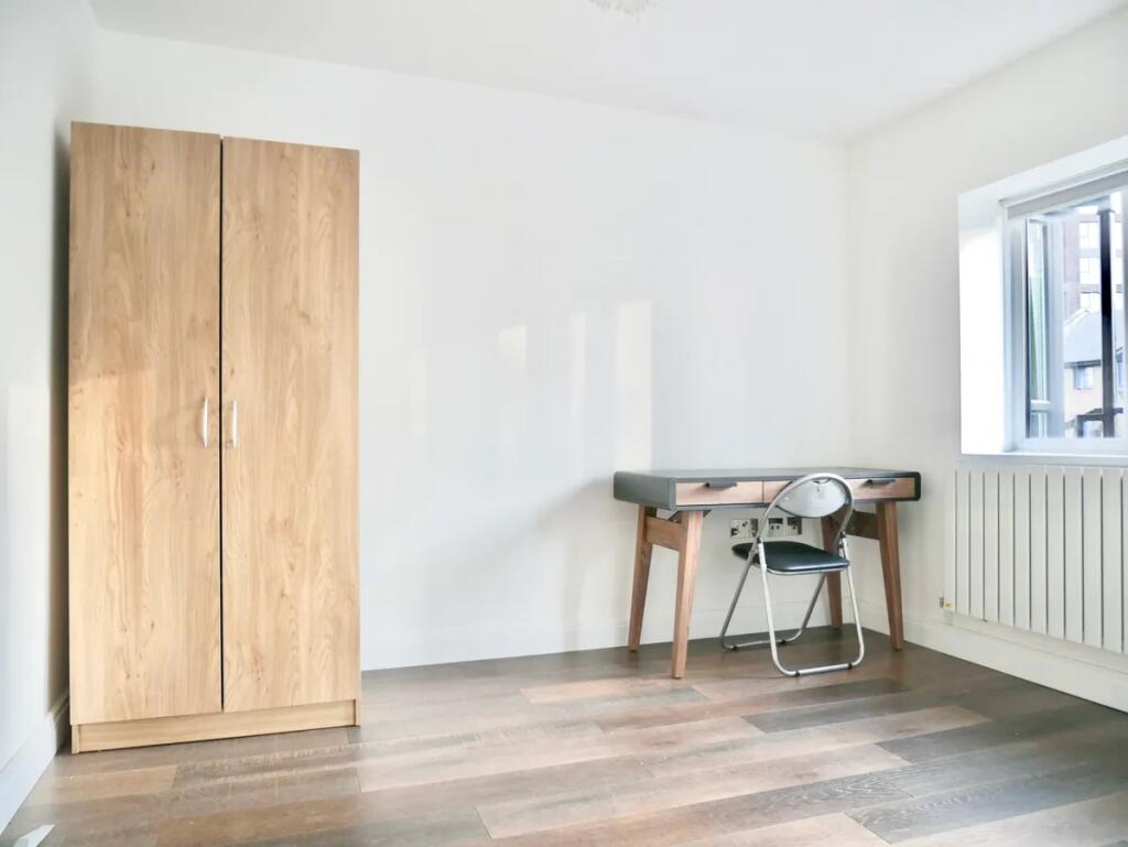 Bright and tidy room featuring a wooden wardrob...