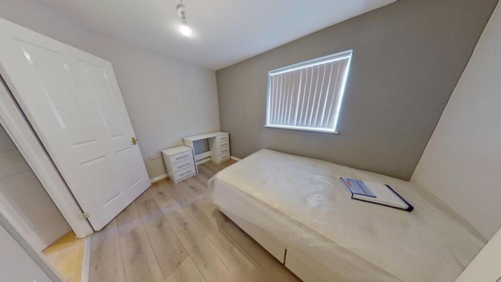 A neat and tidy single bedroom featuring a comf...