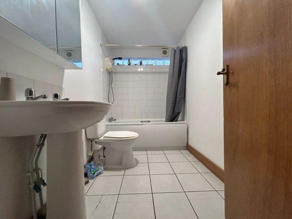 A bright and tidy bathroom featuring a bath and...