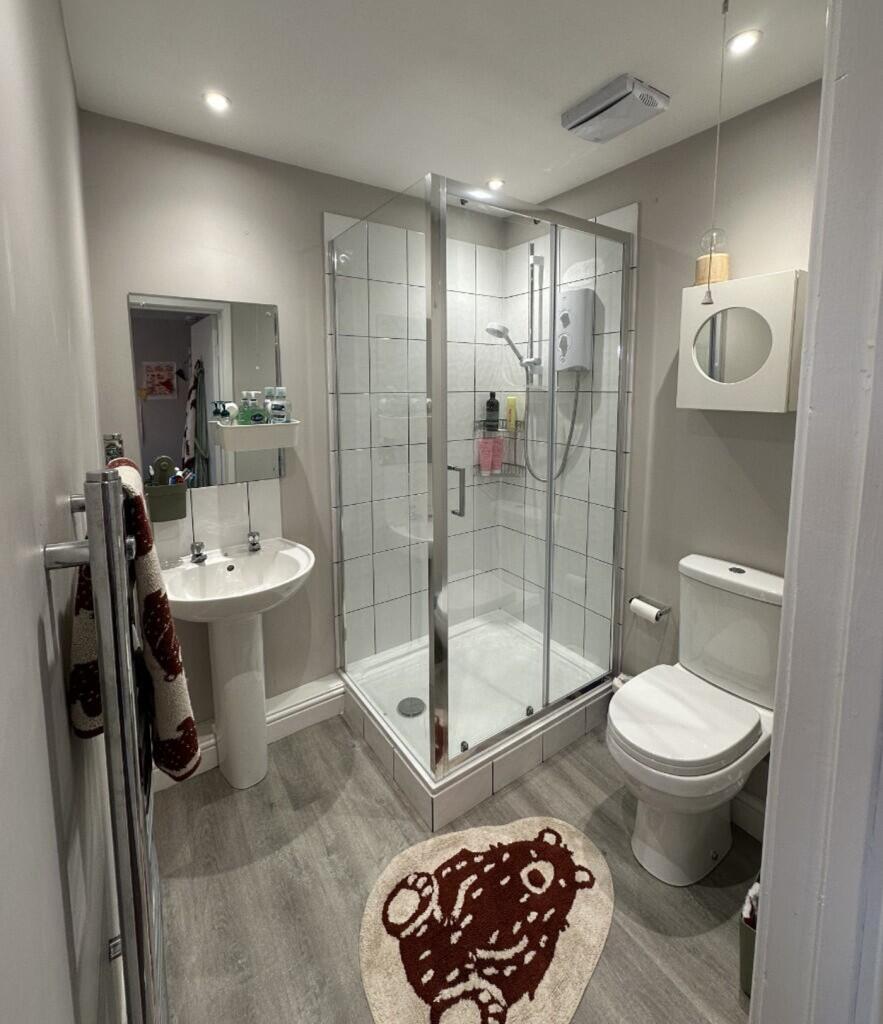 A modern bathroom featuring a sleek glass showe...