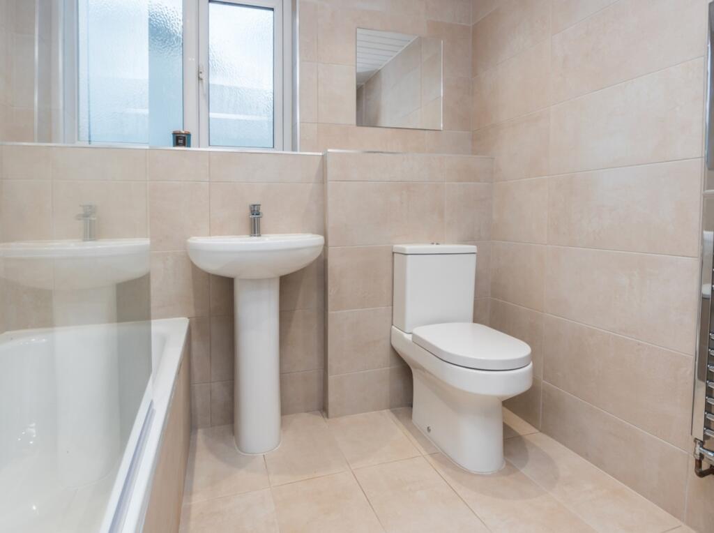 A modern and clean bathroom featuring a bathtub...