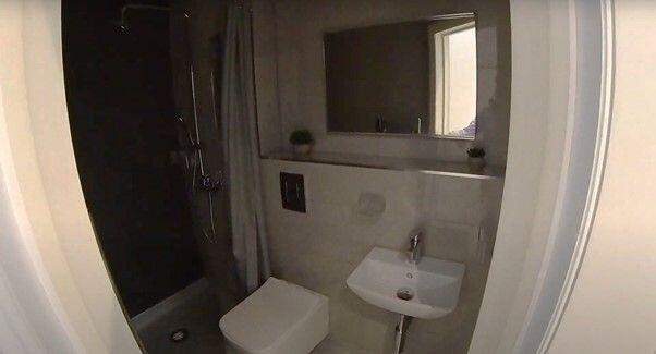 Compact modern bathroom with a walk-in shower, ...