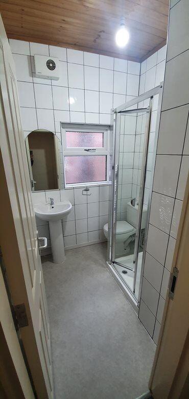 Bright, tiled bathroom with a corner shower enc...