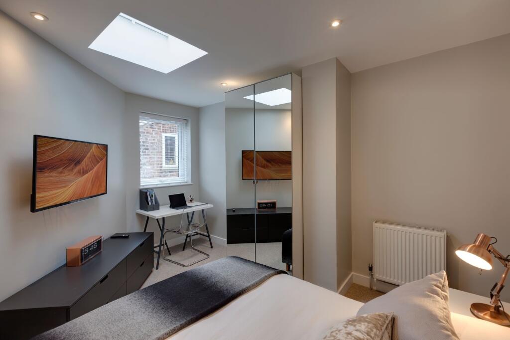 A modern, well-lit bedroom featuring a comforta...