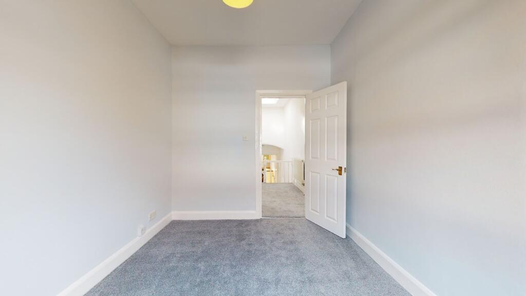 A clean and freshly carpeted single bedroom wit...