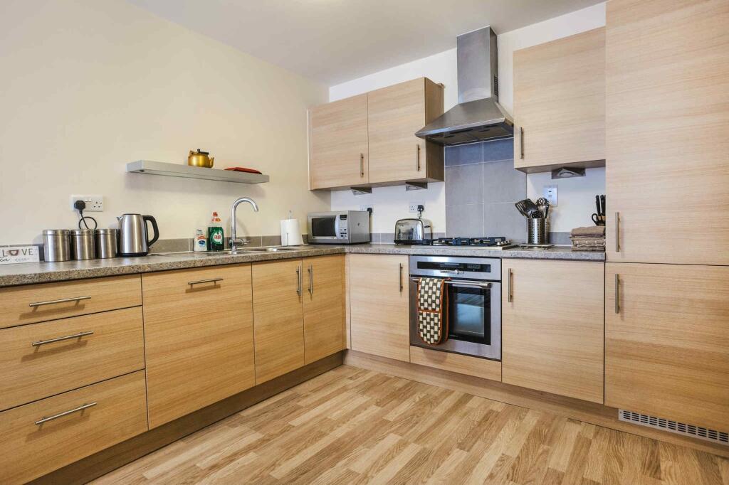 A modern kitchen featuring light wood cabinetry...