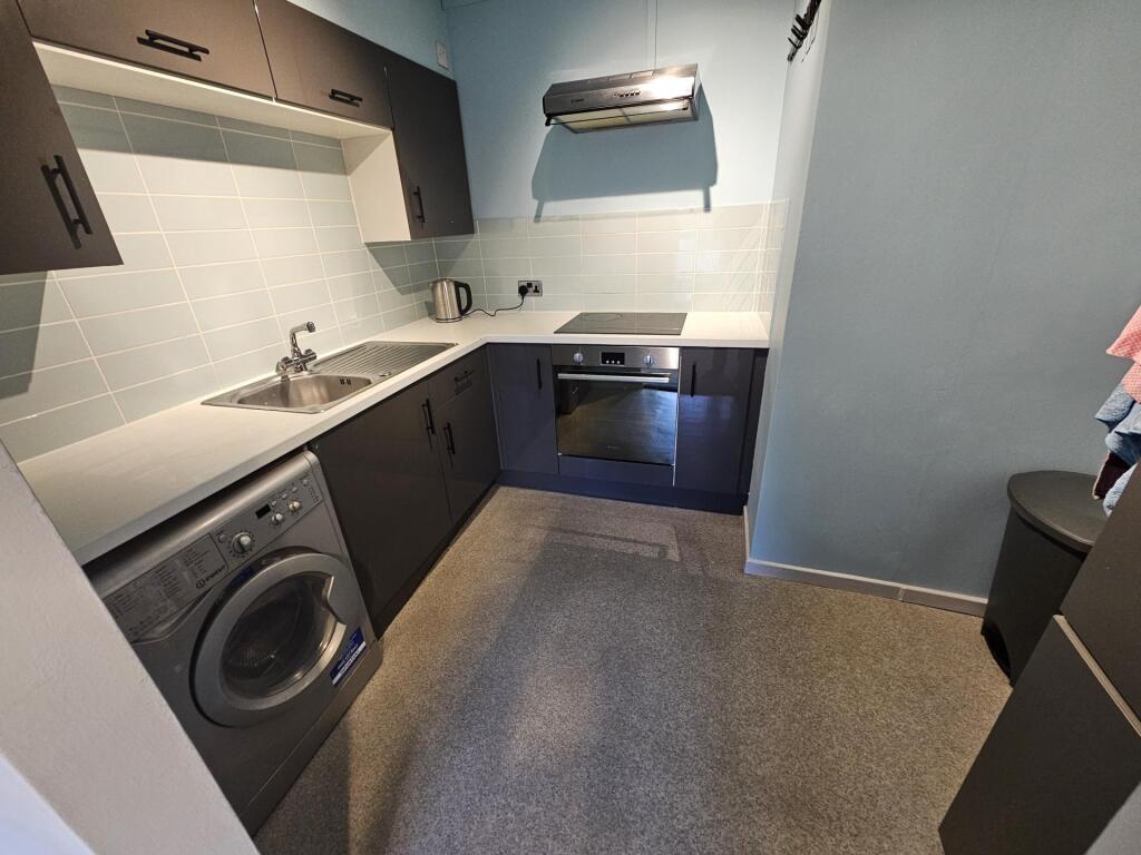 Modern galley kitchen with integrated oven, was...