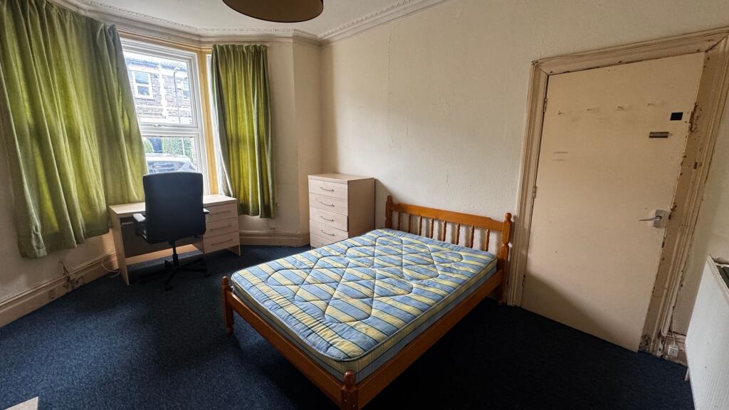 A modest bedroom featuring a single bed with a ...