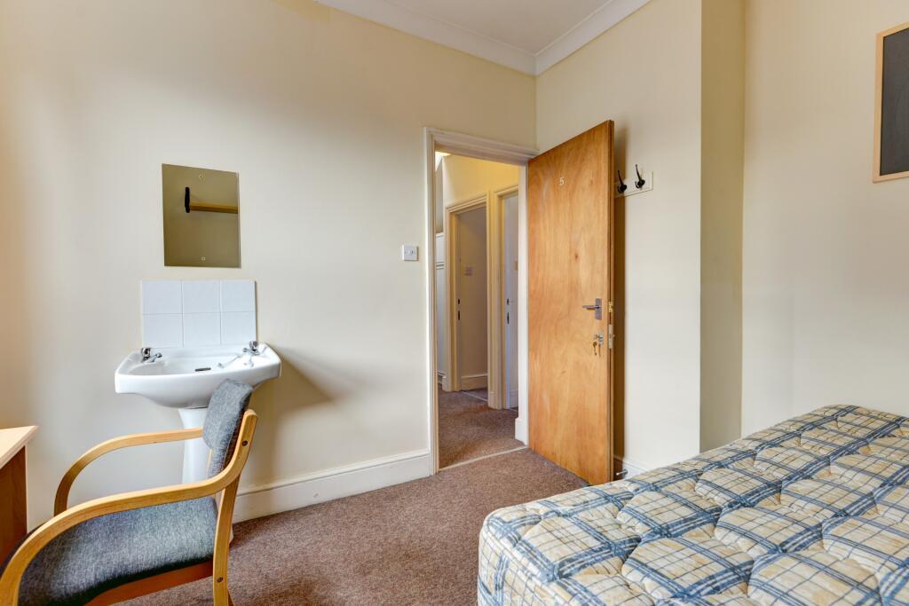 A simple, tidy single bedroom featuring a comfo...