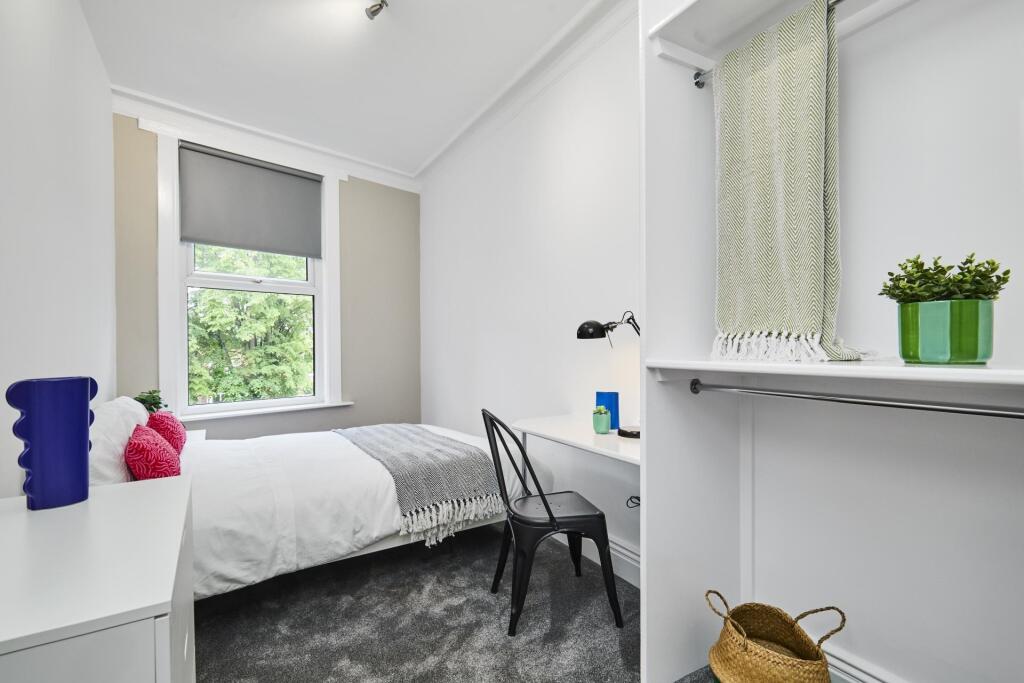 A bright and tidy bedroom featuring a comfortab...