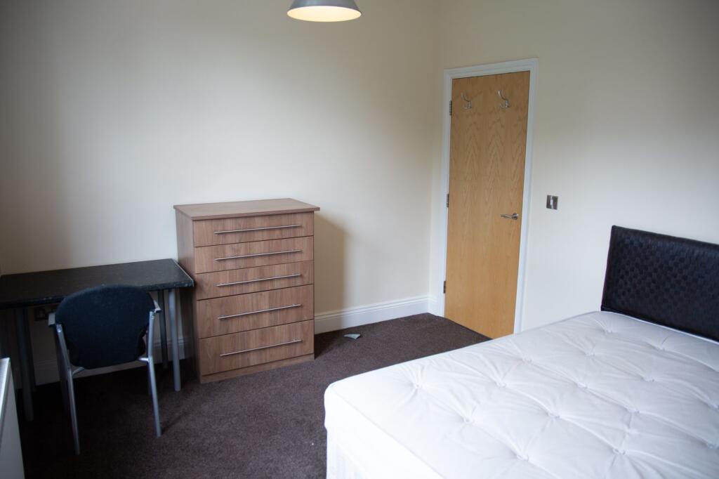 A well-maintained bedroom featuring a bed with ...