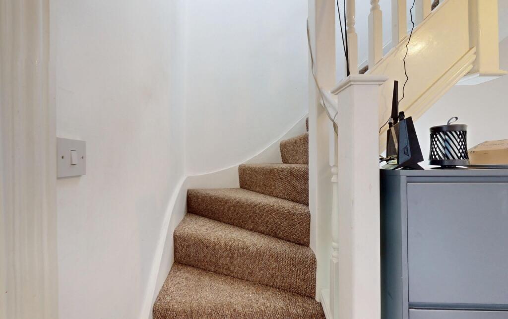 Well-maintained carpeted staircase with white w...