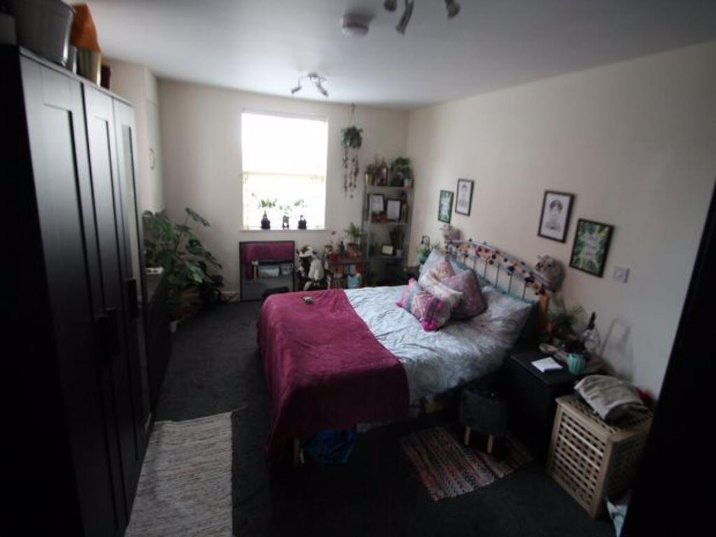 A well-lit, tidy bedroom featuring a comfortabl...